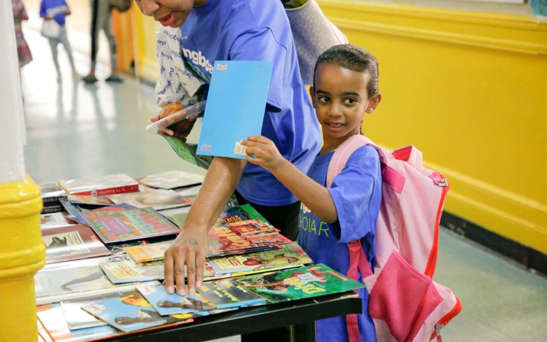 Child and parent choosing a book from a table filled with children’s books at a Springboard Collaborative family workshop
