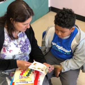 Parent holding a children's book for their child at a Springboard Collaborative family workshop