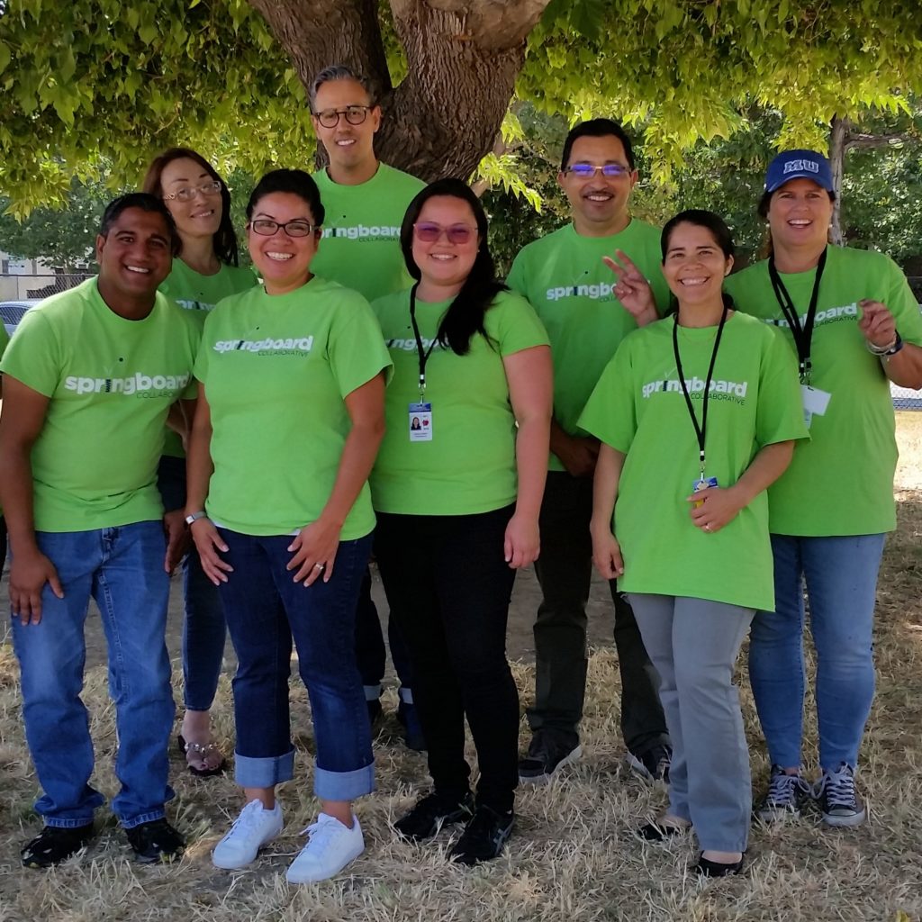 Springboard Collaborative teachers and staff posing outdoors wearing their Springboard Collaborative green T-shirts